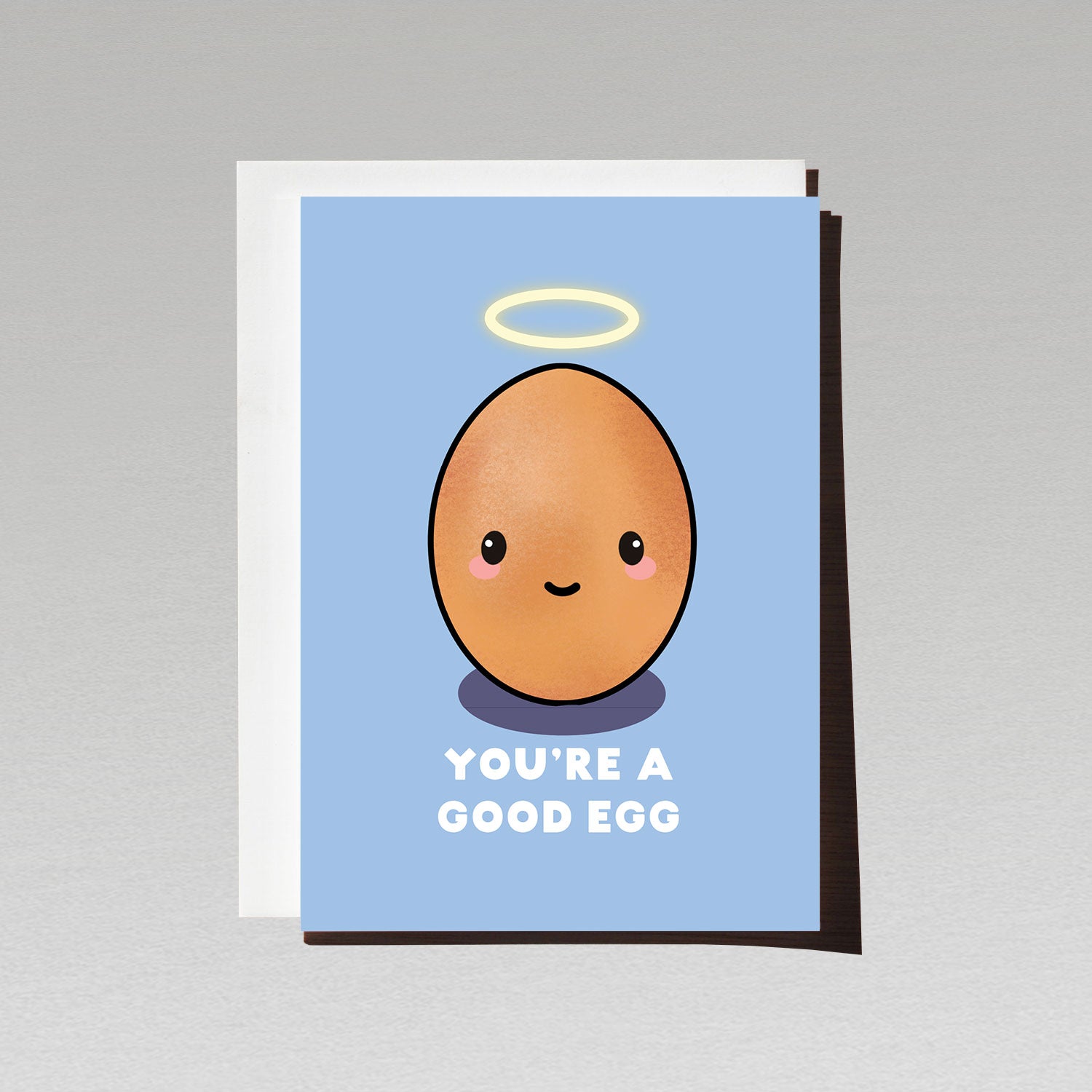 Greeting card with cute smiling brown egg character with angel halo on blue background with text You're a good egg